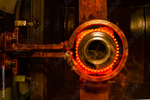 closeup calcining hot metal steel gear parts in a factory induction furnace with smoke photo