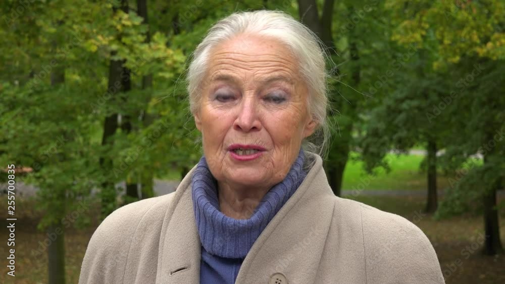 An elderly woman talks to the camera in a park - closeup An elderly woman talks to the camera in a park - closeup