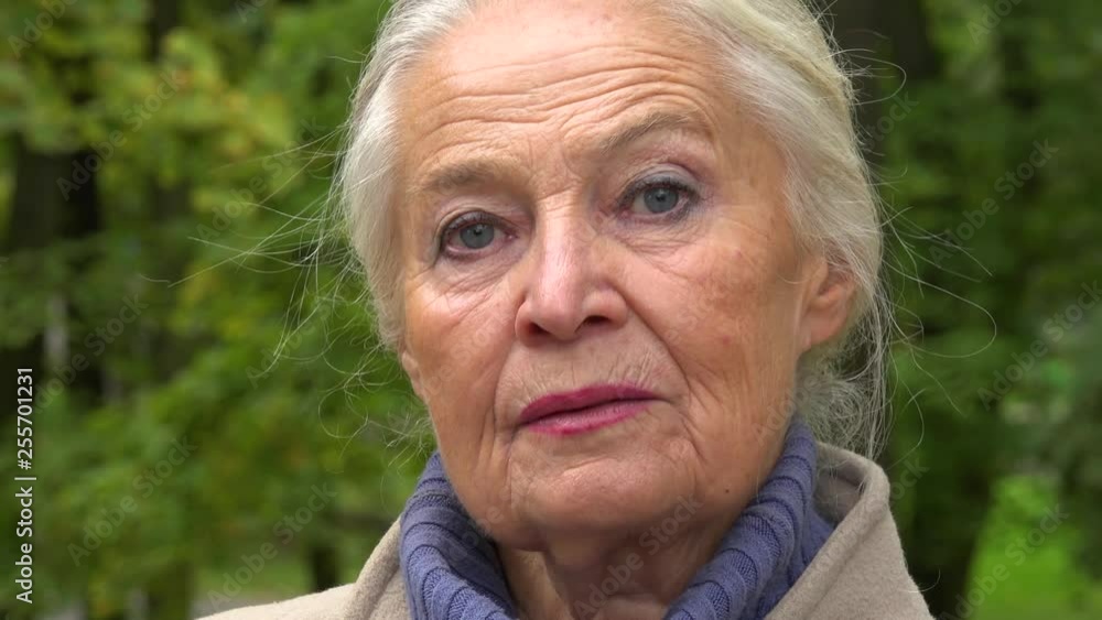 An elderly woman talks to the camera in a park - face closeup An elderly woman talks to the camera in a park - face closeup