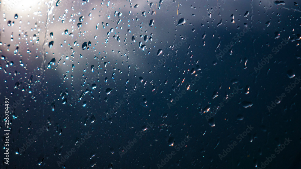 Raindrops on glass and blurred blue sky and clouds Raindrops on glass and blurred blue sky and clouds
