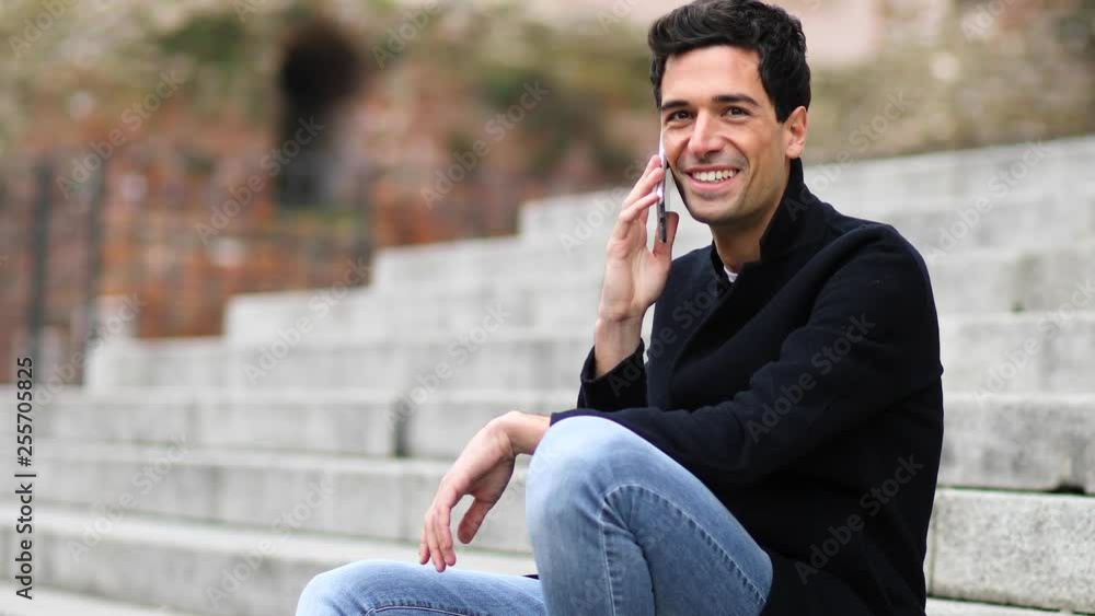 Young man talking on the phone sitting on stairs outdoor Young man talking on the phone sitting on stairs outdoor