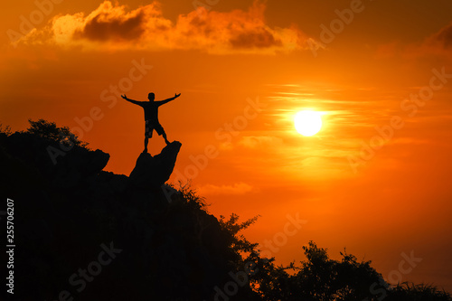 Man standing on the top of the mountain looking at red sky sunset