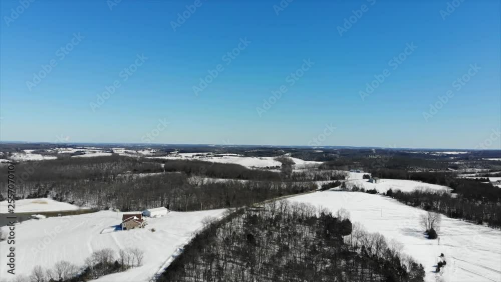 Slow aerial flight over snow covered farmland under a clear blue sky. Slow aerial flight over snow covered farmland under a clear blue sky.