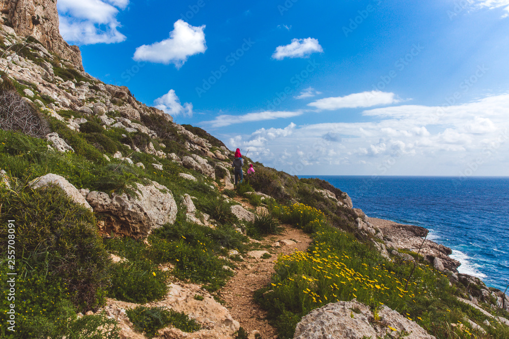 Father and two daughters walk along the path along the sea. Beautiful valley by the sea. Seascape in Cyprus Ayia Napa