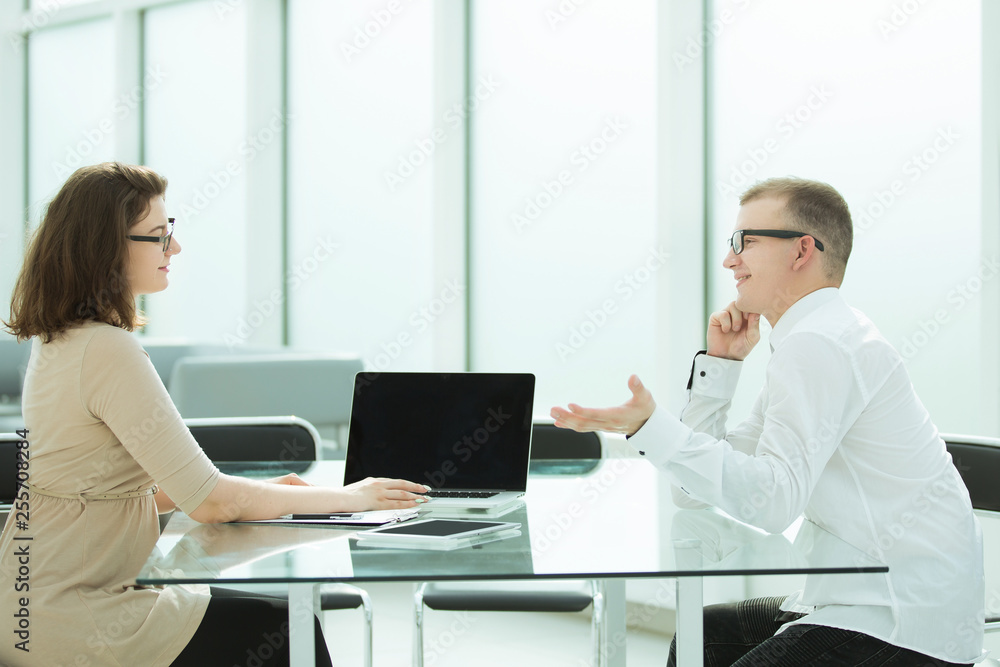 two employees are discussing something sitting at the office table two employees are discussing something sitting at the office table