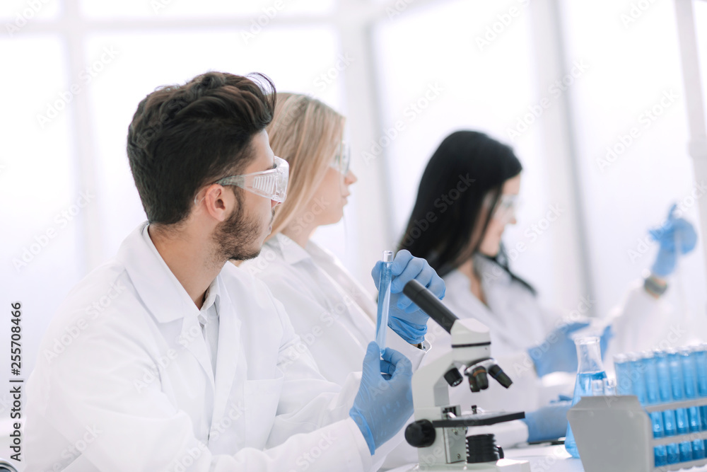 group of young biologists sitting at the laboratory table group of young biologists sitting at the laboratory table