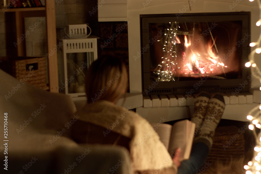 single woman reading a book in front of a fireplace on a long winter night