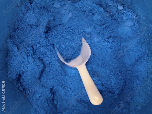 Close up of dry ultramarin pigment powder with a white spoon 