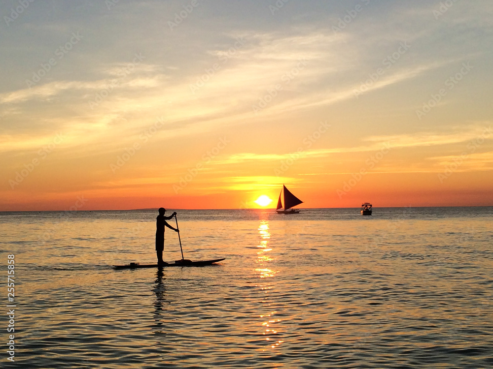 Man on a sup board in the water at sunset