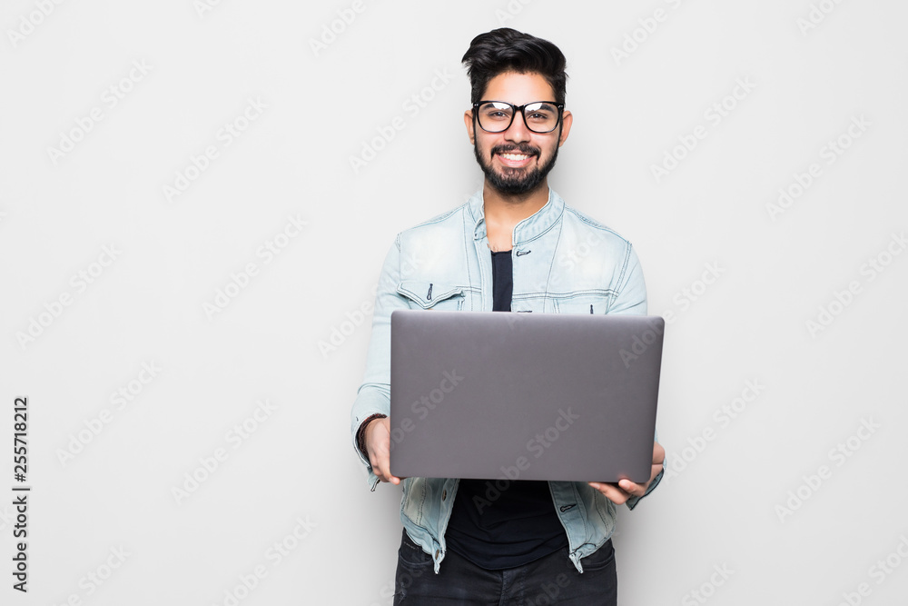 Young indian man in eyesglasses and casual wear holding laptop white standing isolated on white background Young indian man in eyesglasses and casual wear holding laptop white standing isolated on white background