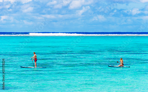 Man paddle on a surfboard in the ocean, Cook Islands, South Pacific. Copy space for text.