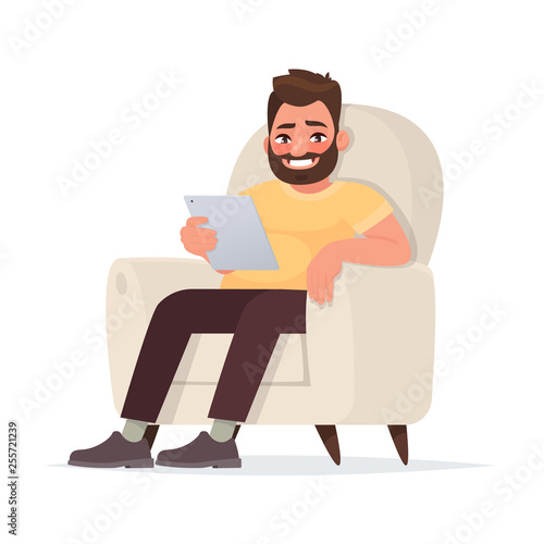 Internet addiction. A waste of time on social networks. A man holds a tablet sitting on the couch