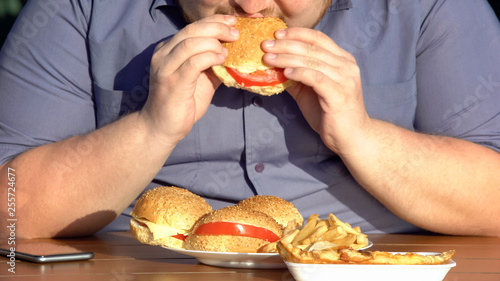 Obese hungry man eating fatty burgers  unhealthy food addiction  overweight
