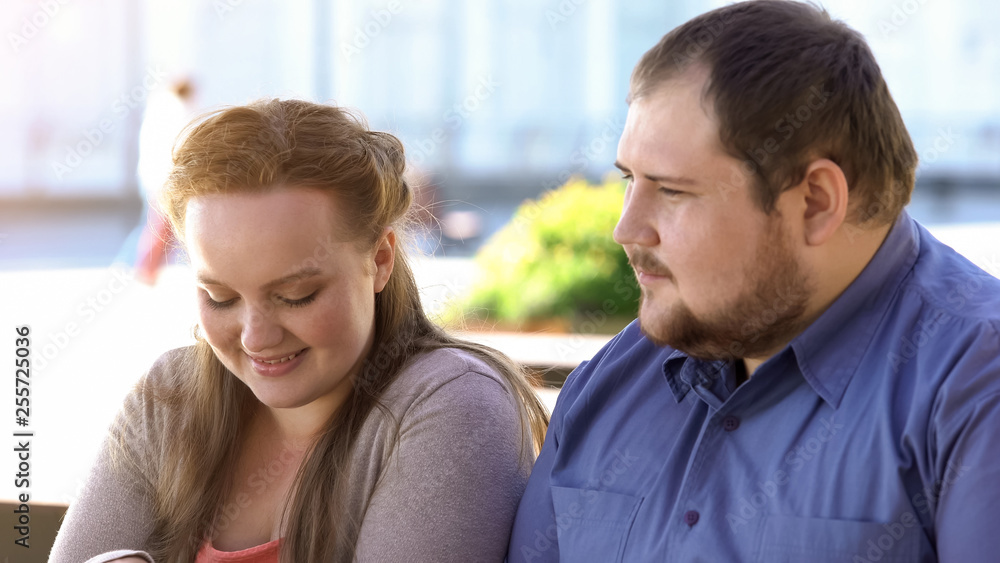 Shy fat couple sitting in outdoor cafe during romantic date, awkward situation Shy fat couple sitting in outdoor cafe during romantic date, awkward situation