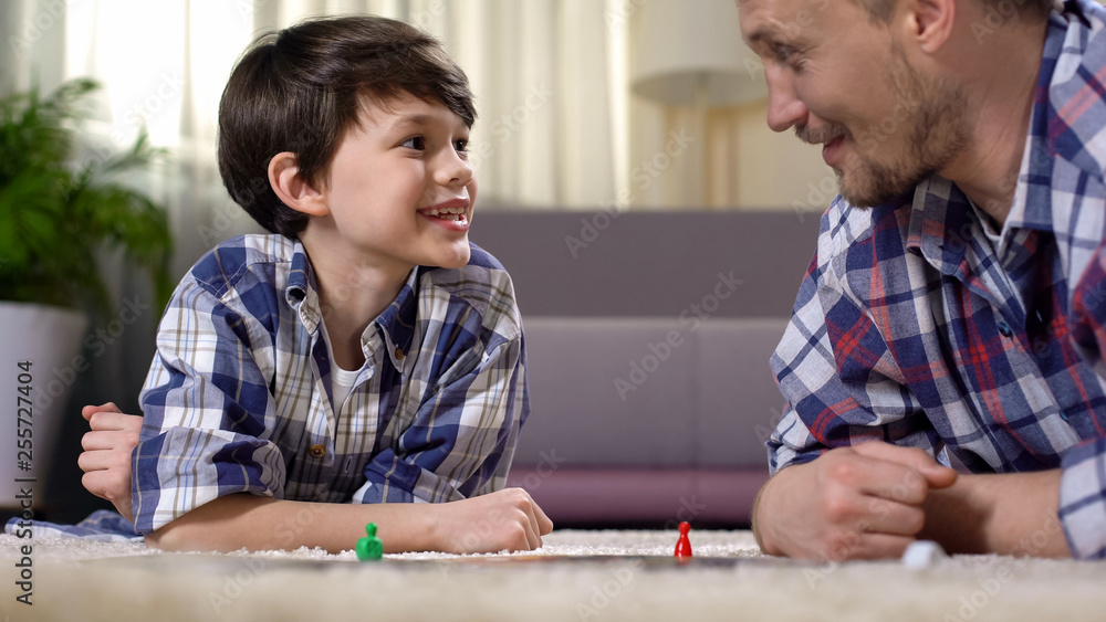 Father and son playing exciting board game, parent developing boys skills Father and son playing exciting board game, parent developing boys skills