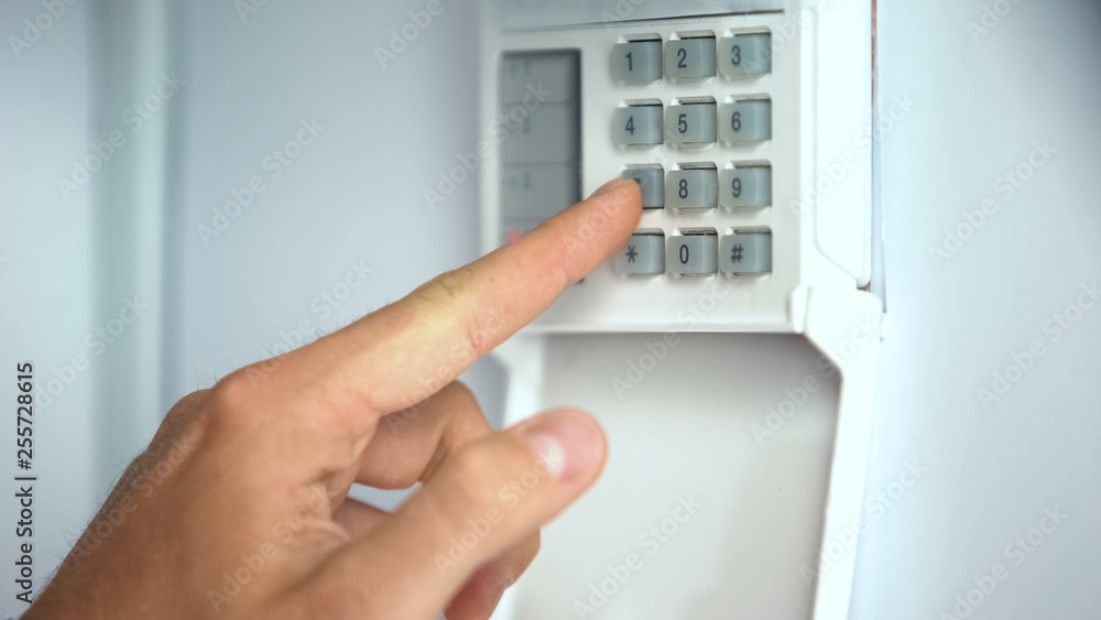 Man entering password on home security system, robbery protection, close up Man entering password on home security system, robbery protection, close up