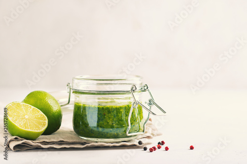 Green sauce chimichurri with fresh herb and spices in jar on white background photo