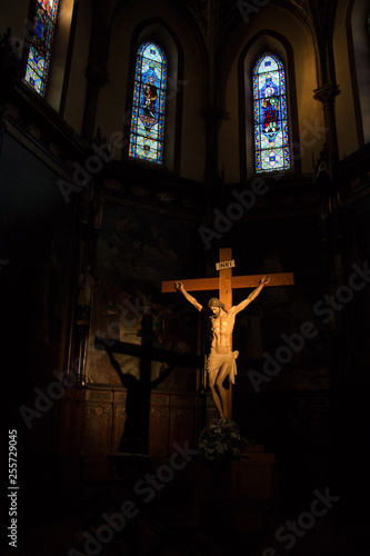 Light of the church on crucifix with its projected shadow and stained glass in the background
