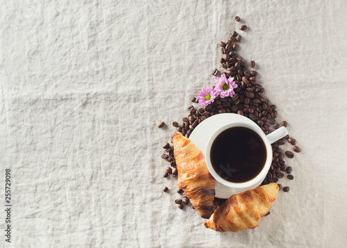 Breakfast concept with cup of coffee, croissants, flower and coffee beans on table,  morning photo