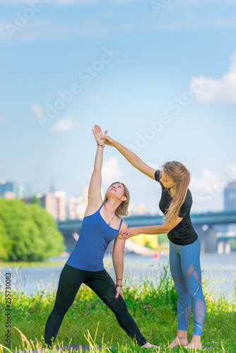 Active women in nature do yoga. Mature woman with an individual trainer.