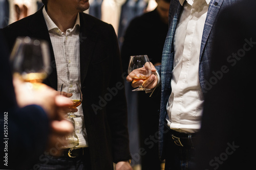 People standing chatting at a bussiness dinner holding whisky and wine glass tasting and degustating food chef's food