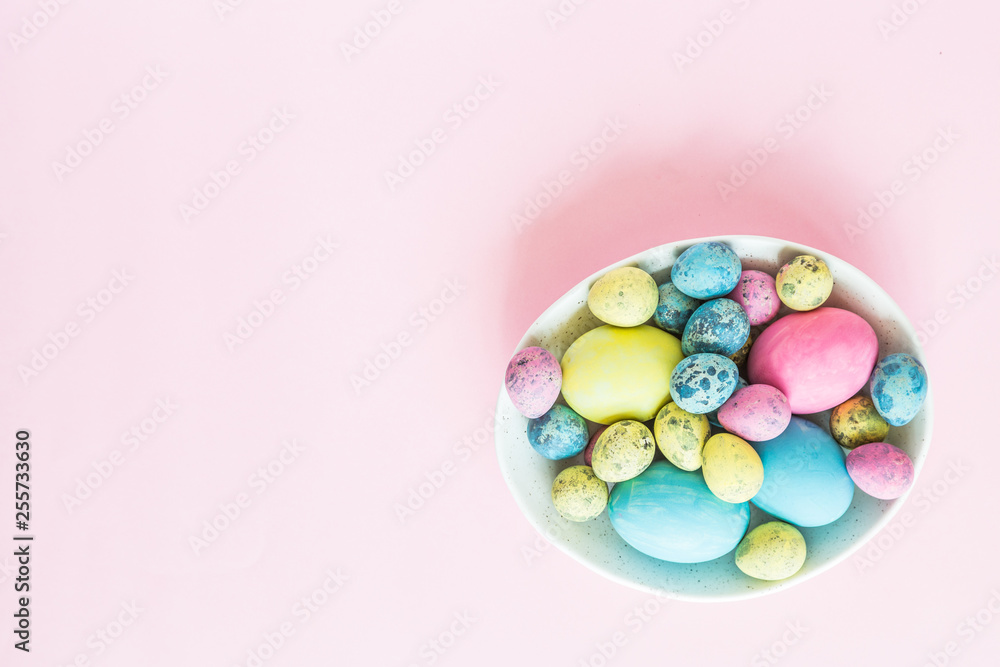 Painted easter eggs in white plate lying on pink background. Top view. Flat lay. Place for text