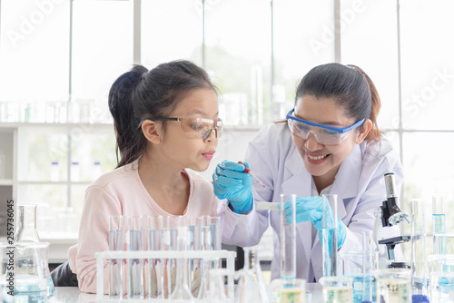 Image of woman teacher and girl student in lab science class. Young girl excited in lab class with scientist.