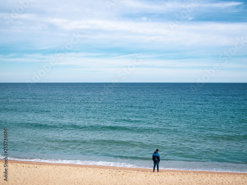 Lonely thinking young man standing on the beach in sunny day, copy space