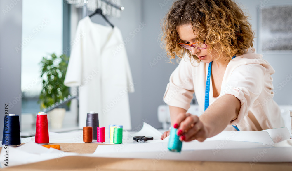 Professional female tailor over work desk at fashion design workshop Professional female tailor over work desk at fashion design workshop