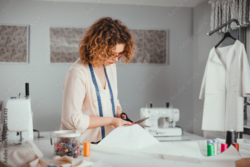 Professional female tailor over work desk at fashion design workshop Professional female tailor over work desk at fashion design workshop