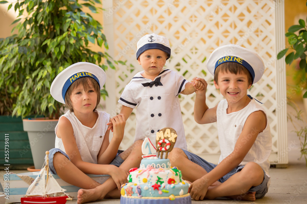 Sweet baby boy and his brothers, celebrating first birthday with sea theme cake and decoration Sweet baby boy and his brothers, celebrating first birthday with sea theme cake and decoration