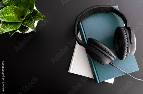 audiobook concept with overhead shot of headphones on stack of books on black background photo