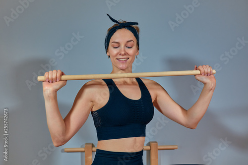 Beautiful girl - trainer in sports short top and sports leggings smiling is standing at the simulator for body stretching. Healthy lifestyle concept. Copy space photo