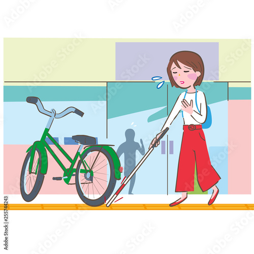 点字ブロックを白杖で確認しながら歩く女性と障害になっている自転車