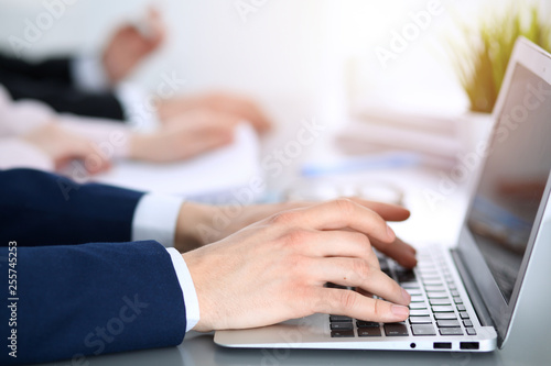 Group of business people working together in office. Man hands typing on laptop computer
