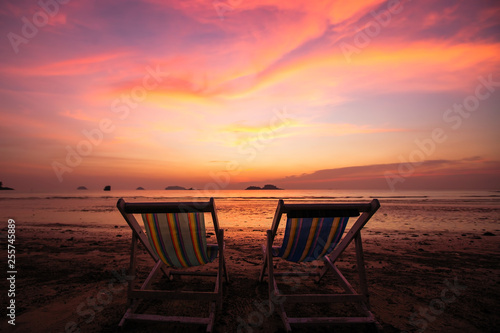 Couple of sun loungers on the beach during amazing sunset. © De Visu