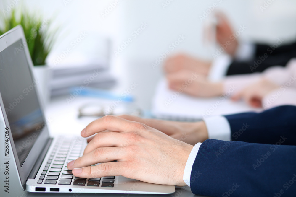 Group of business people working together in office. Man hands typing on laptop computer Group of business people working together in office. Man hands typing on laptop computer