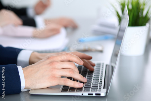 Group of business people working together in office. Man hands typing on laptop computer