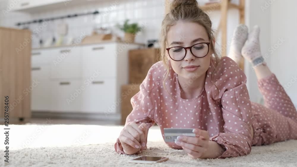 Young woman shopping online. Girl using smart phone in home. Girl with smartphone tablet and bank card indoors. Easy pay using digital gadget. Young woman shopping online. Girl using smart phone in home. Girl with smartphone tablet and bank card indoors. Easy pay using digital gadget.