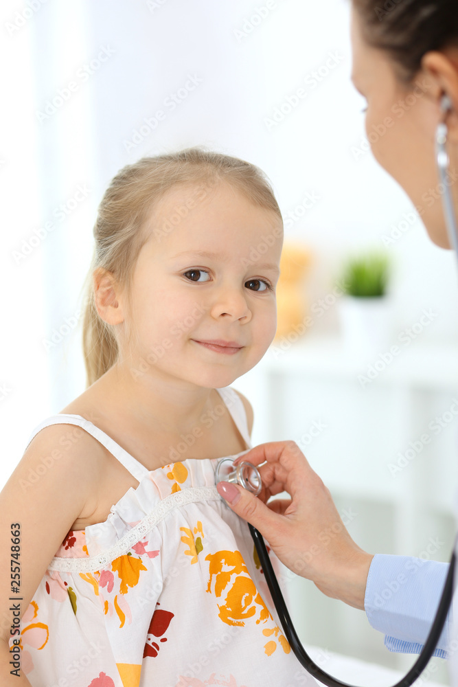 Doctor examining a little girl by stethoscope. Happy smiling child patient at usual medical inspection. Medicine and healthcare concepts Doctor examining a little girl by stethoscope. Happy smiling child patient at usual medical inspection. Medicine and healthcare concepts