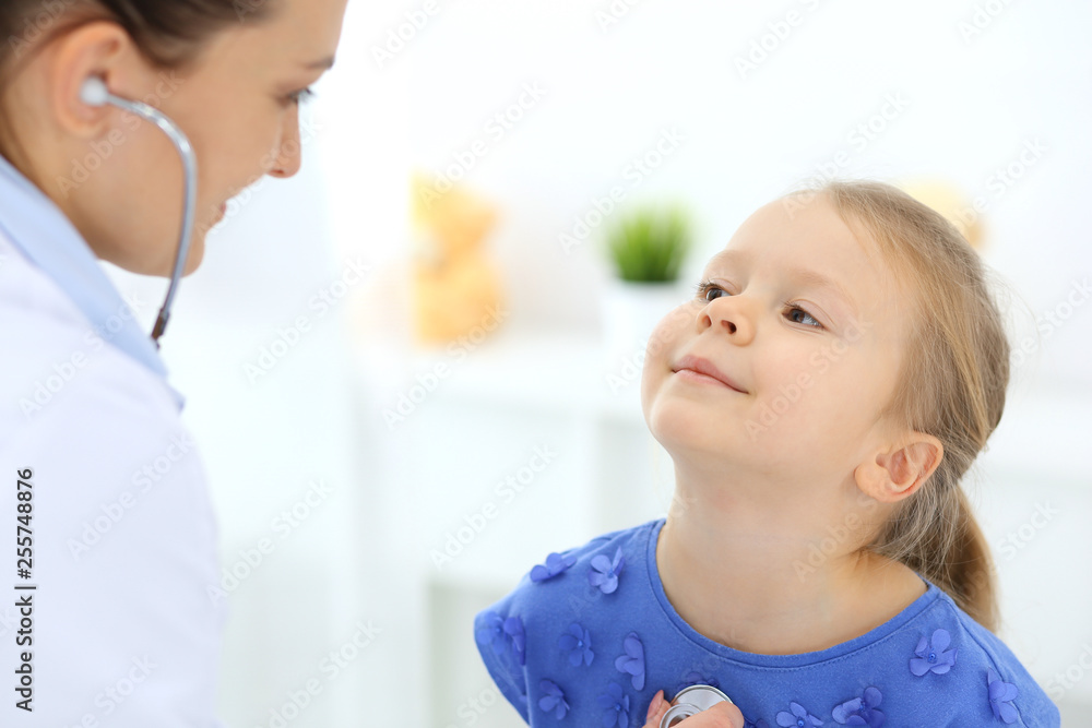 Doctor examining a little girl by stethoscope. Happy smiling child patient at usual medical inspection. Medicine and healthcare concepts Doctor examining a little girl by stethoscope. Happy smiling child patient at usual medical inspection. Medicine and healthcare concepts