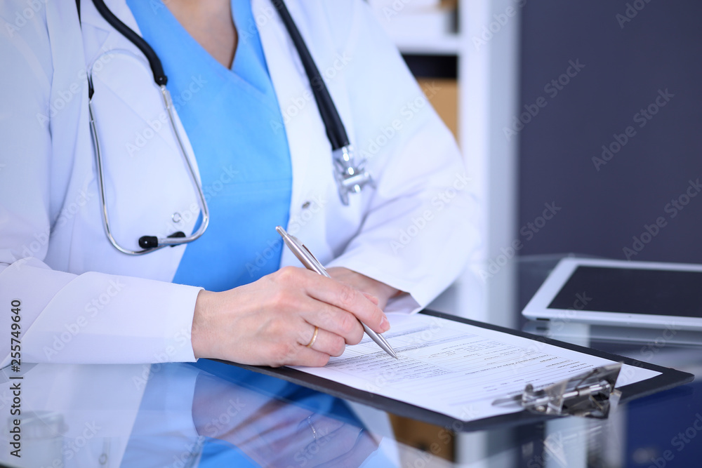 Female doctor filling up medical form on a clipboard, closeup. Healthcare, insurance and medicine concept Female doctor filling up medical form on a clipboard, closeup. Healthcare, insurance and medicine concept