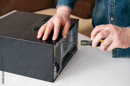 Technician disassemble computer with a screwdriver for problems diagnostic and repair photo