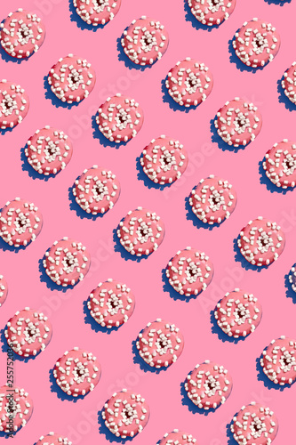 Food design with tasty pink glazed donut on coral pink pastel background top view pattern