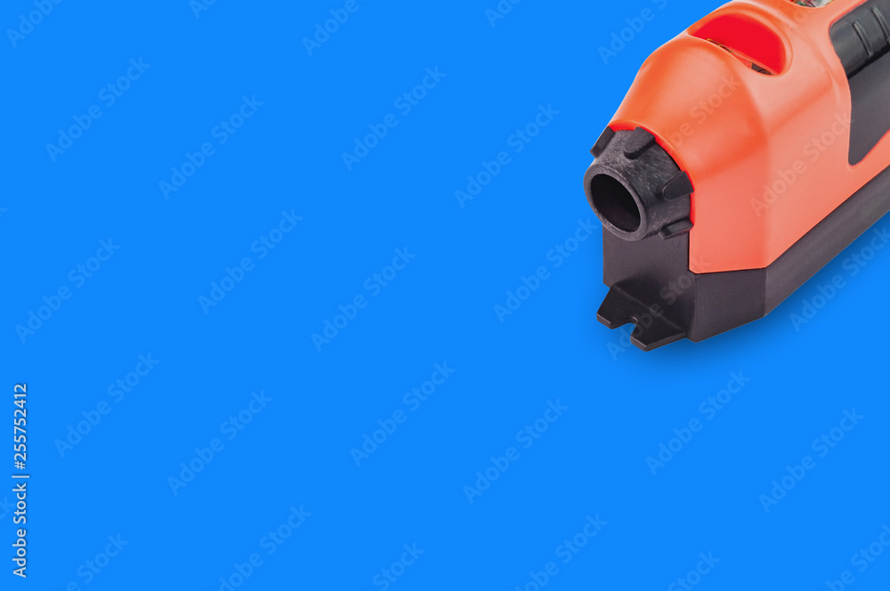 One red and black plastic laser level with water bubble for horizontal or vertical measure on blue background with copy space for your text. Building or repair concept One red and black plastic laser level with water bubble for horizontal or vertical measure on blue background with copy space for your text. Building or repair concept