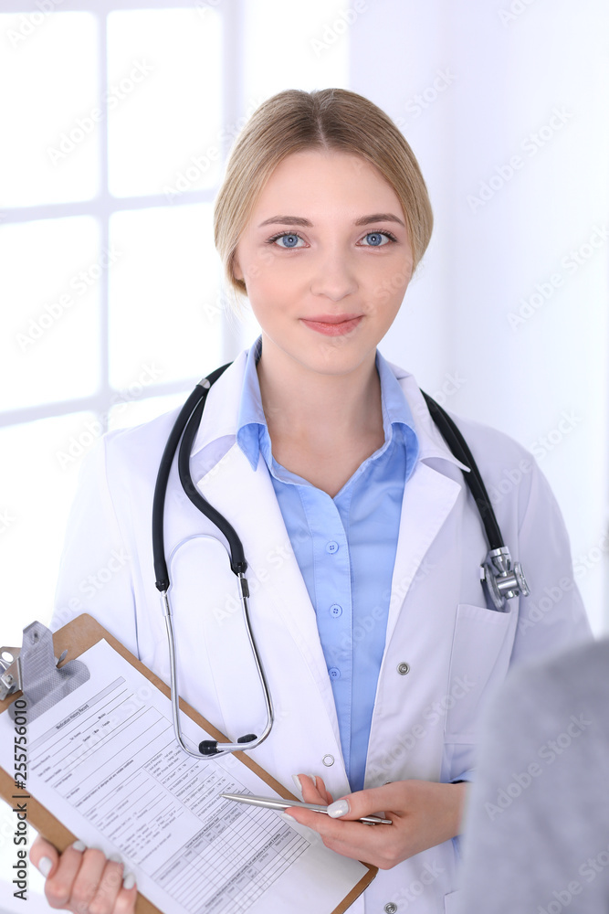 Young woman doctor and patient looking at medication history records while standing straight in hospital Blue colored blouse of therapist looks good. Medicine and healthcare concept Young woman doctor and patient looking at medication history records while standing straight in hospital Blue colored blouse of therapist looks good. Medicine and healthcare concept