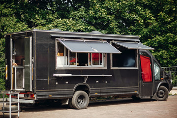 Food van truck. Stylish black mobile food truck with burgers and asian food at street food festival. Summer eating market in the city. Space for text, menu