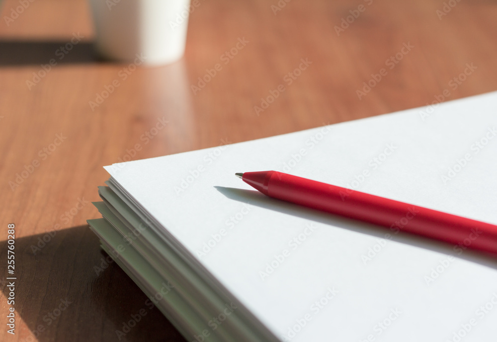 a stack of white paper and a pen on the table