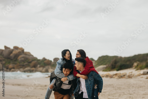 Group of friends piggybacking on the beach