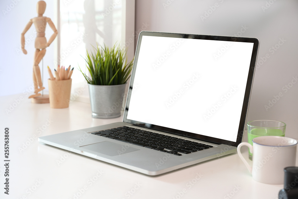 Office desk table with blank screen laptop and poster.
